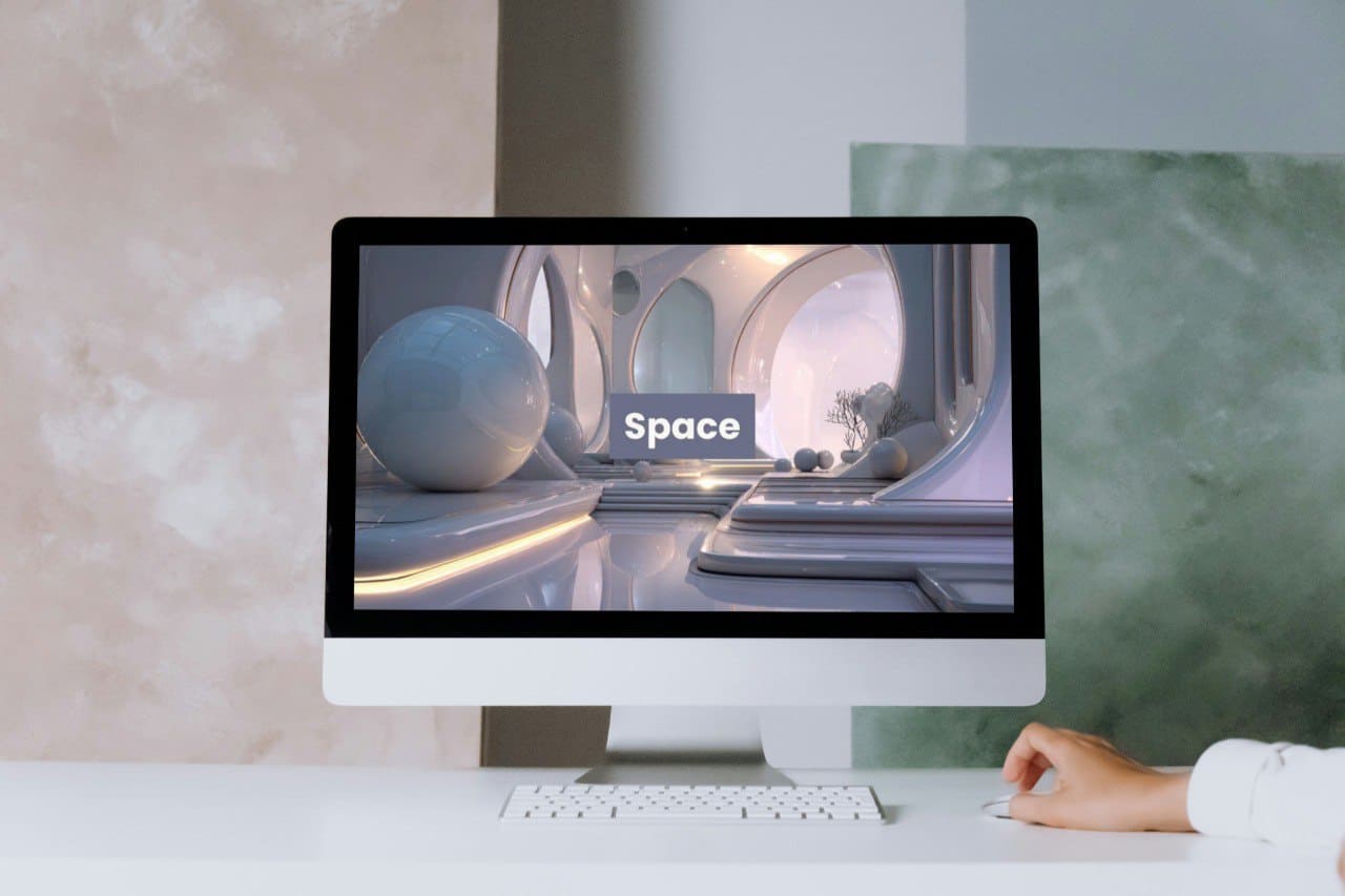 Computer monitor displaying a 3D modeling course cover 'Space' on a desk with a person's hand.