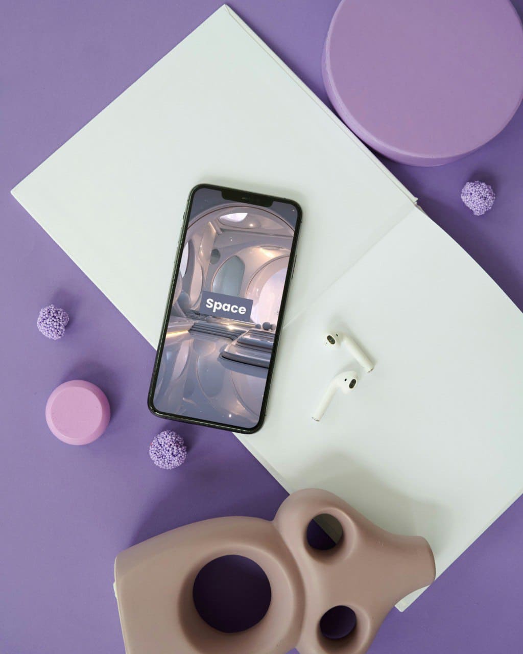 Smartphone with 'Space' 3D modeling course on screen, earphones, and decorative items on a purple surface